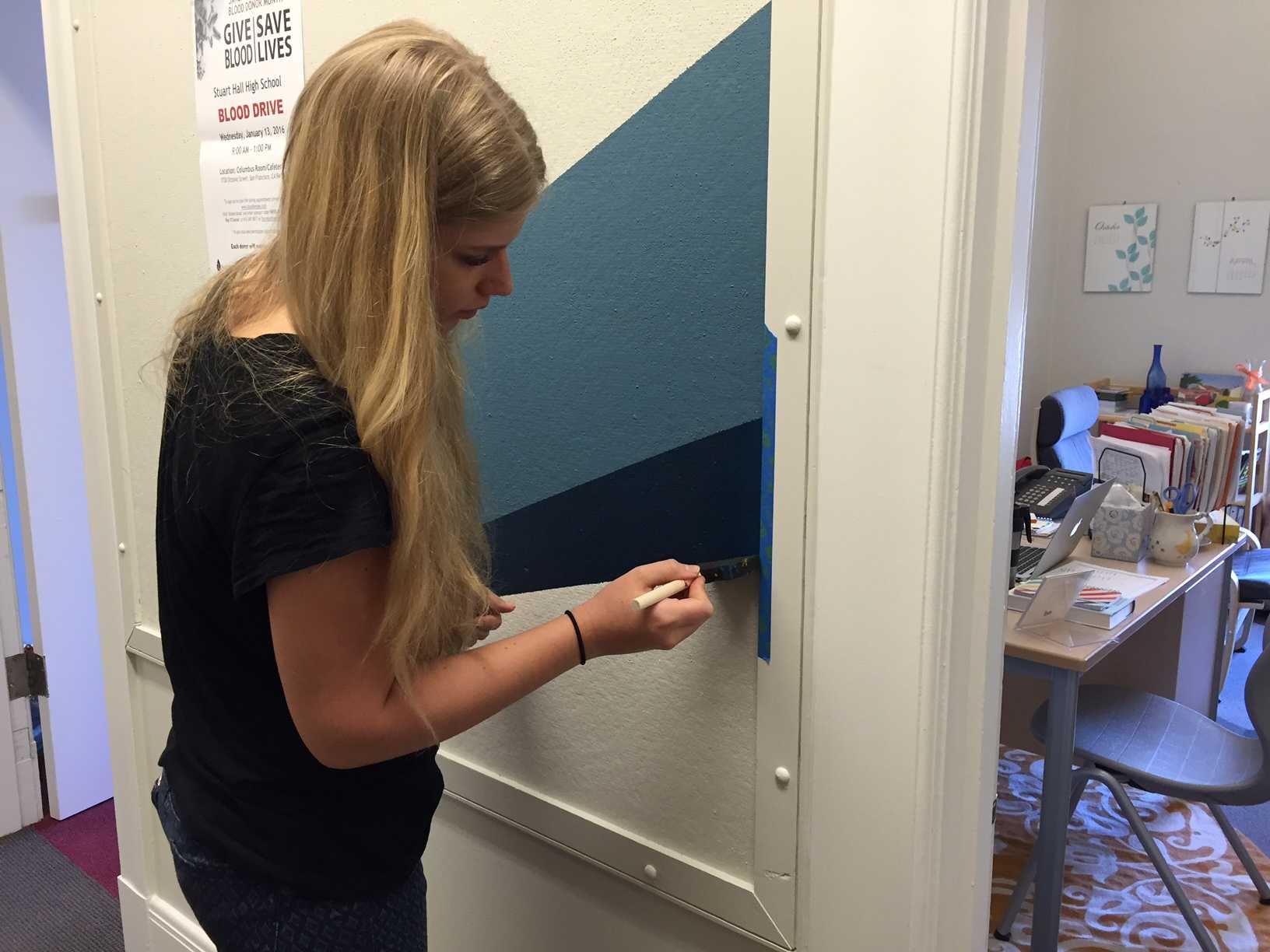 Alumna Sabine Kelly ('15) touches up part of the mural on the third floor near the faculty room. The doors in front of the hallway were removed before the painting of the new mural.