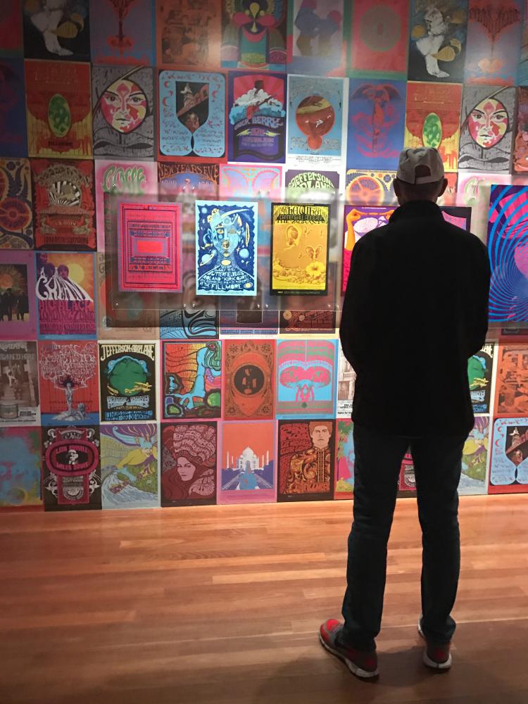 A de Young Museum visitor views vintage music posters at “The Summer of Love Experience: Art, Fashion, and Rock & Roll.