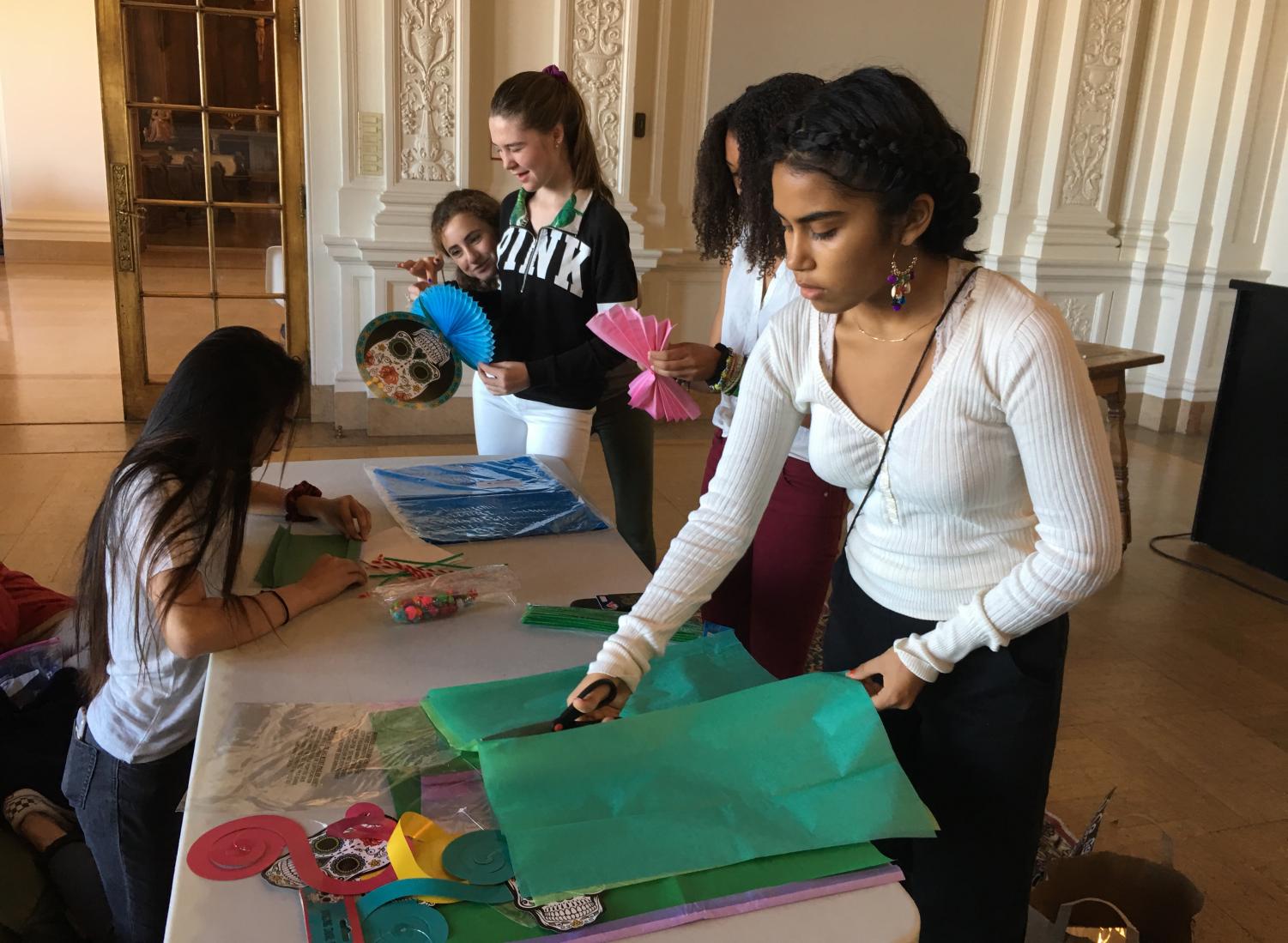 Malinalli Cervantes cuts colorful tissue paper for carnation flower decorations during the POCSU meeting. Sophomore Ryann Minnis taught the members how to fold the tissue paper to make the flowers.