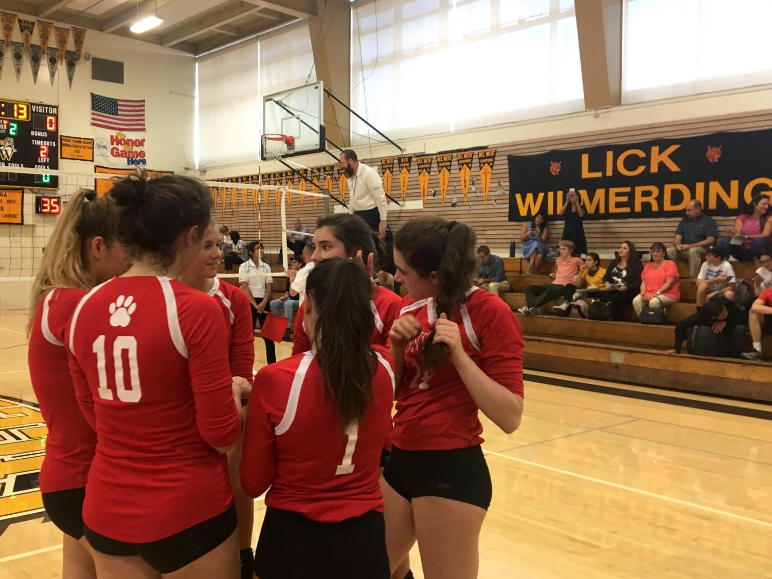 Varsity volleyball's starting lineup huddles before restarting the game after a timeout was called. The team lost 3-0 against Lick Wilmerding.