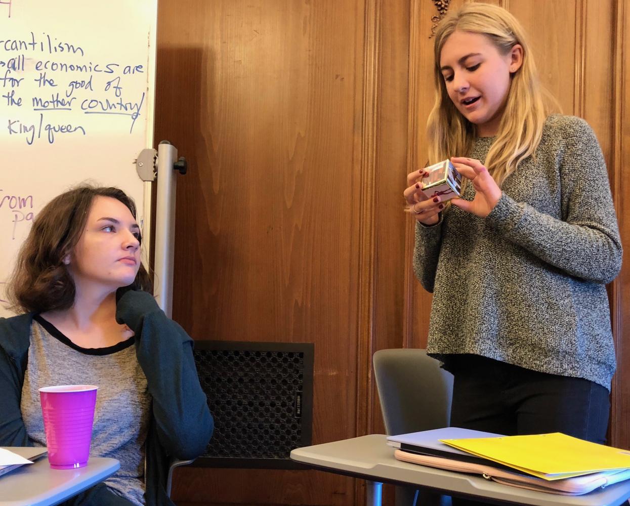 Freshman Lola Morrell listens to Grace Krumplitsch present her self-portrait to her G Period English I class. Many students opted to draw their self-portraits but others made 3-D designs like Krumplitsch's cube.