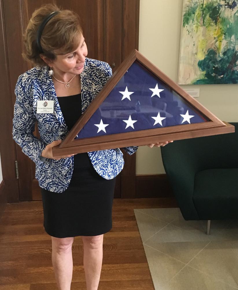 President Ann Marie Krejcarek holds the flag gifted to the school by House Minority Leader Nancy Pelosi. The Capitol Flag program allows members of Congress to request a flag to be flown over the U.S. Capitol on behalf of a constituent.