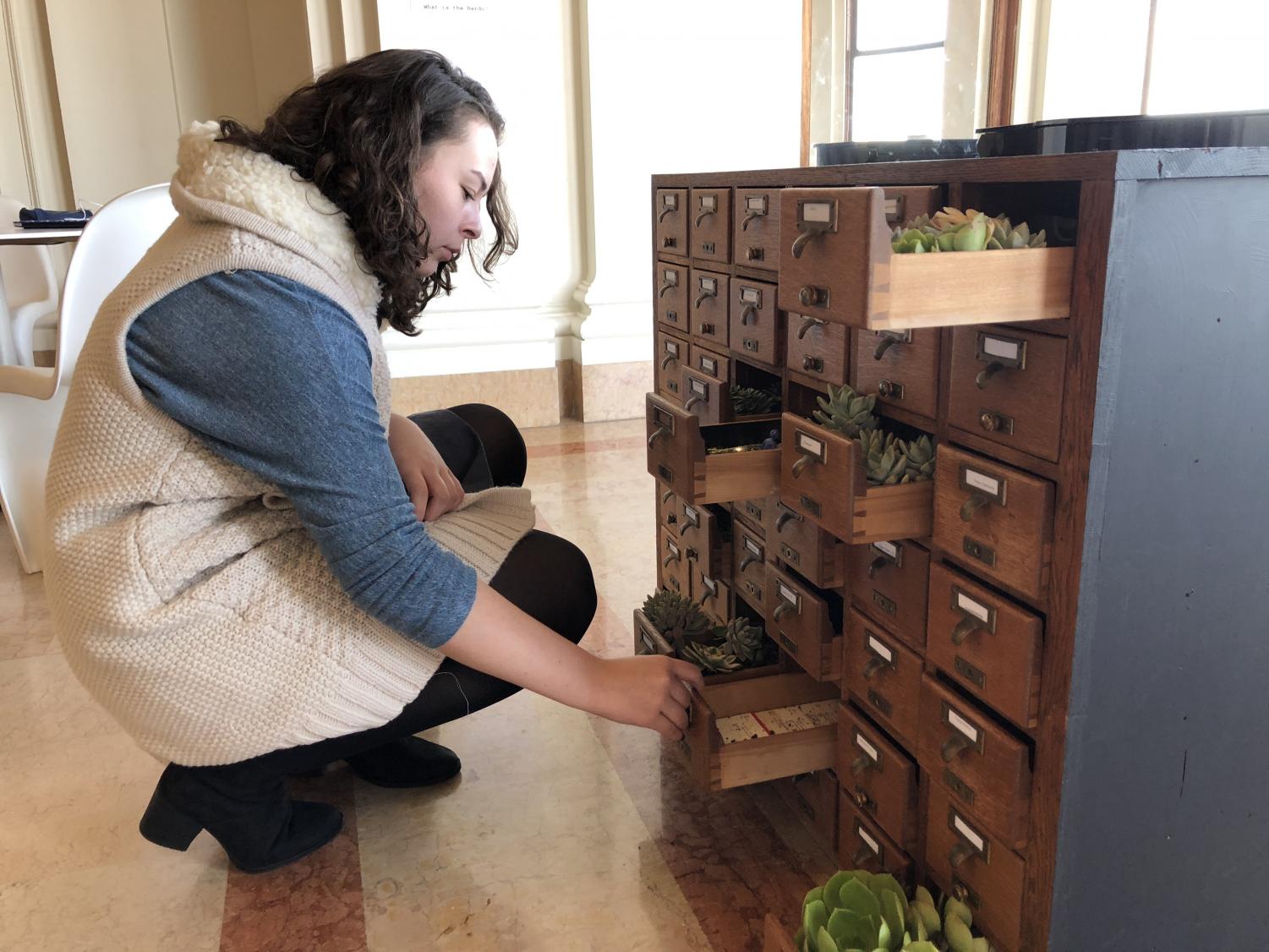 Sophomore Dena Silver looks inside the drawers of the Bardo. The art piece will stay in the Belvedere until the end of the book fair.