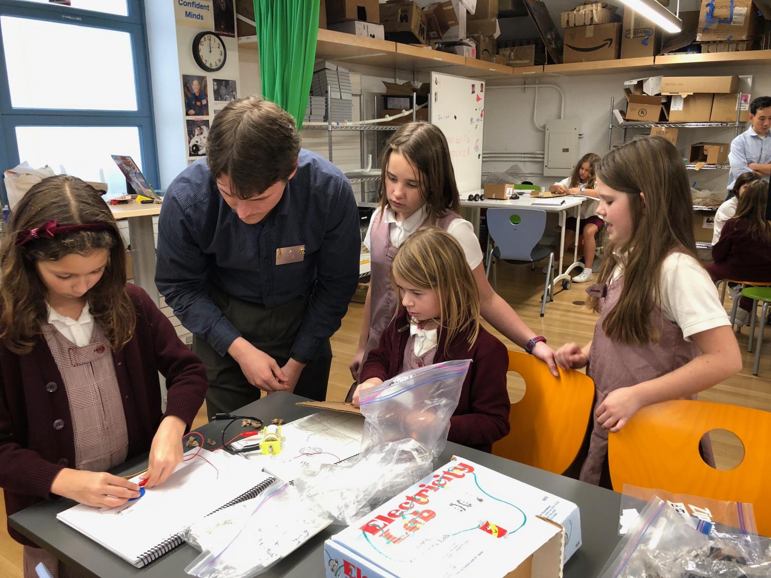 Robotics teacher Chris Person-Rennell helps fourth grade students to assemble parts of their simple circuits. Freshmen and sophomores were also in the classroom to assist the elementary students.