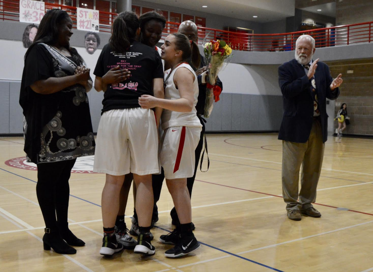 Junior Jordan Russell hugs senior Grace Ainslie after Ainslie was recognized in the Senior Night ceremony. Russell and Ainslie have been on varsity together for two years, and Monday was the final night that the two played on the same team.