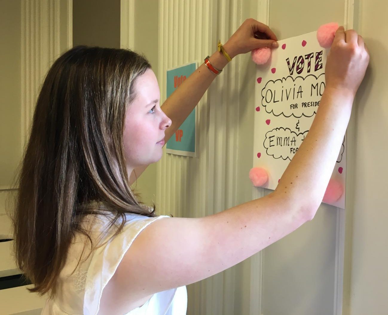 Junior Emma Hubbard hangs a campaign poster in the Center for her and junior Olivia Mohun, who are running as a President and Vice President team. Elections will be held in the Chapel on Monday, and results will be posted by the end of the day.