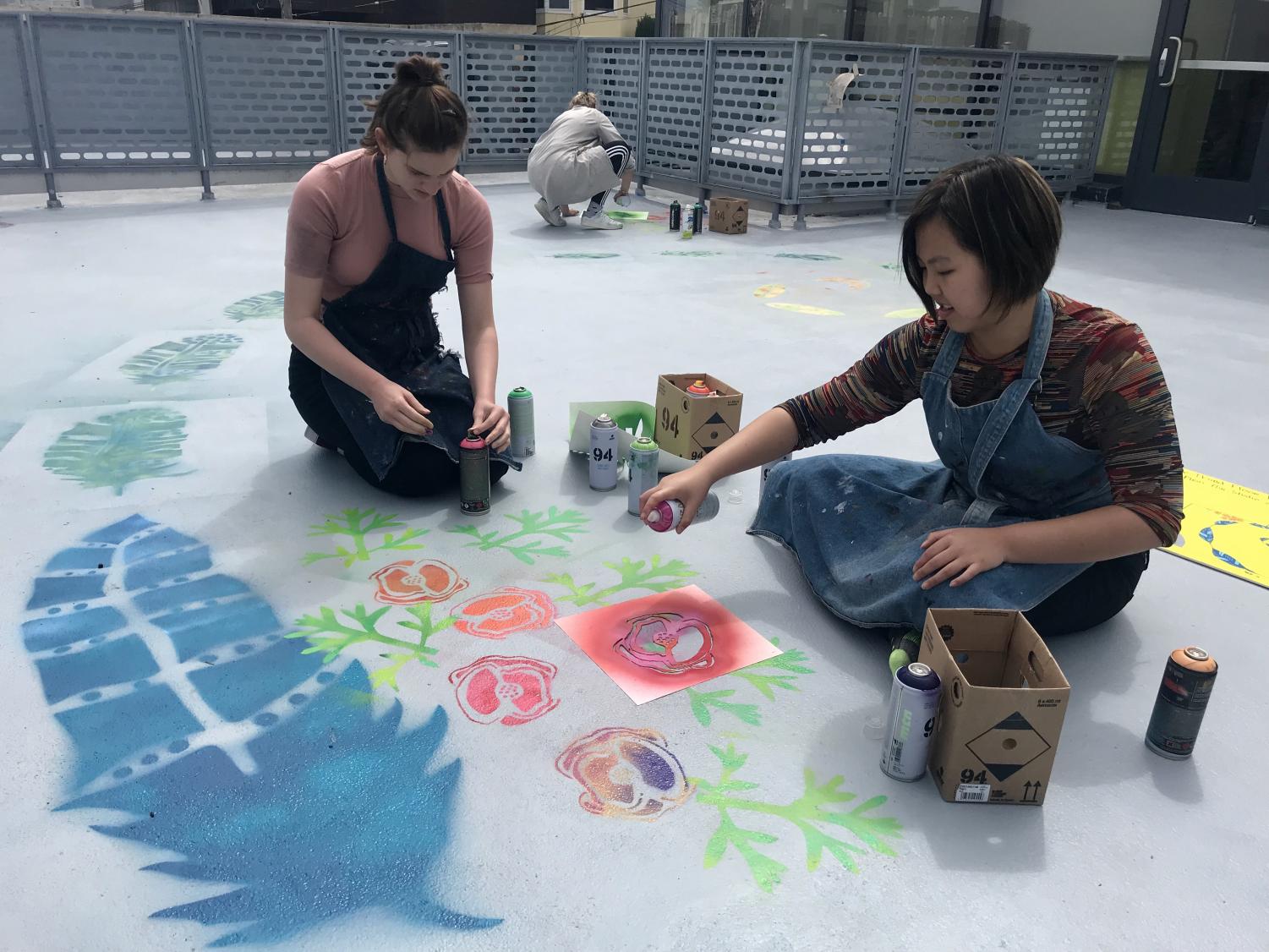 Sophomores Cat Webb-Purkis and Abby Widjanarko spray paint California poppies and bald eagle feathers on the art terrance floor. The mural incorporates all elements of STEAM.