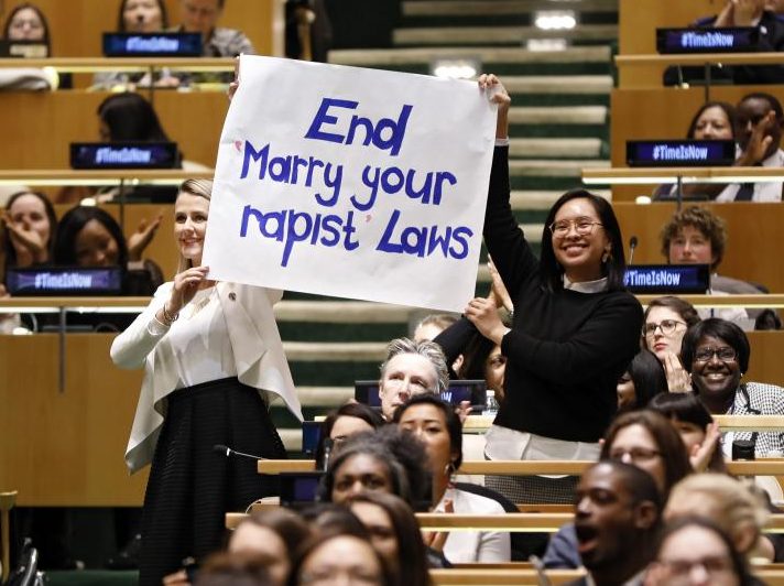 Joëlle Santos '09, right, holds up a sign at the International Women's Day celebration. Other U.N. Women raised awareness for movements such as #MeToo and #TimesUp.