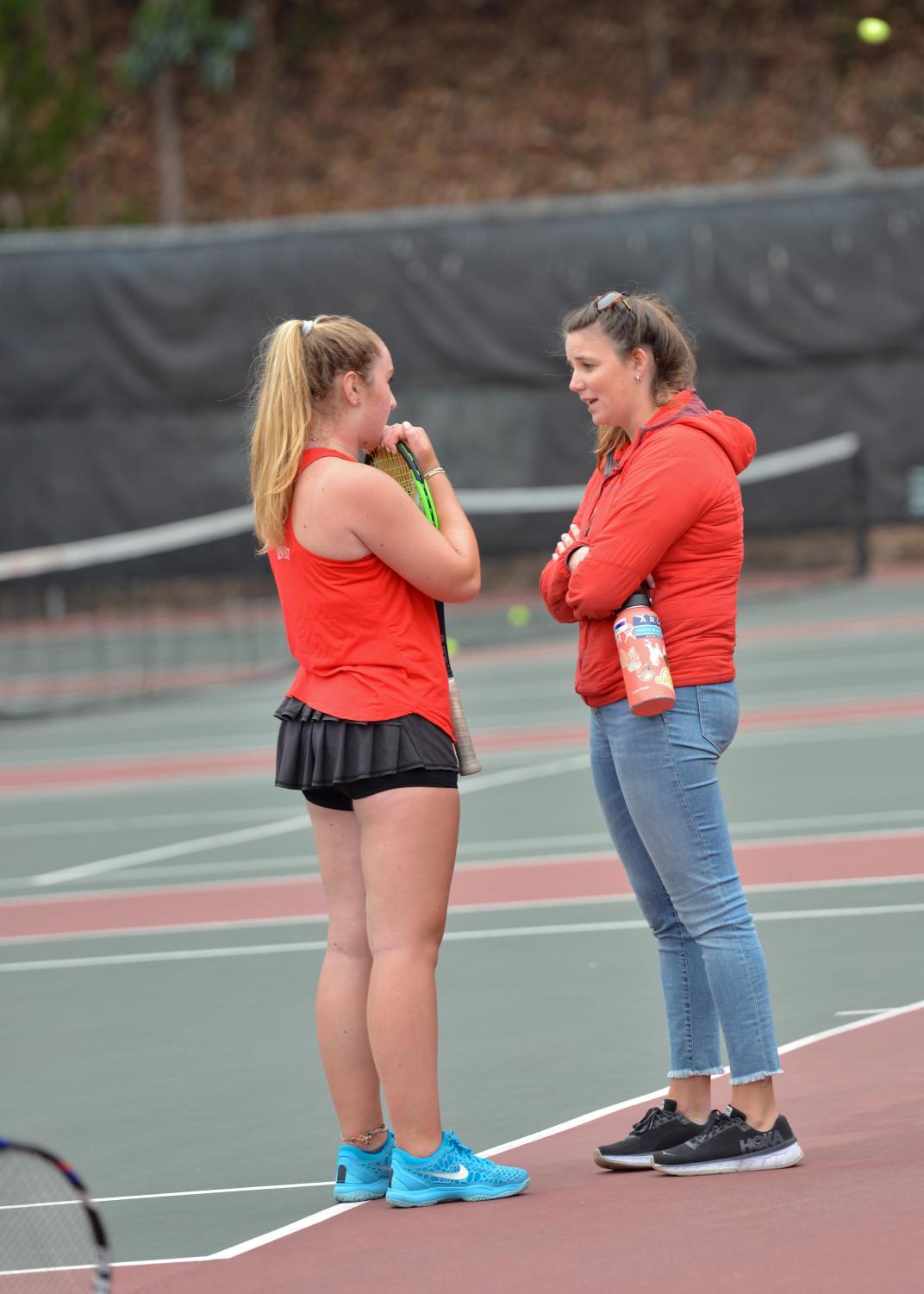 Varsity tennis coach Erin Minuth '11 chats with freshmen Elise Vulakh during a match against Sacred Heart Cathedral Preparatory. This is Minuth's first year as coach, and the team has a 5-0 record.