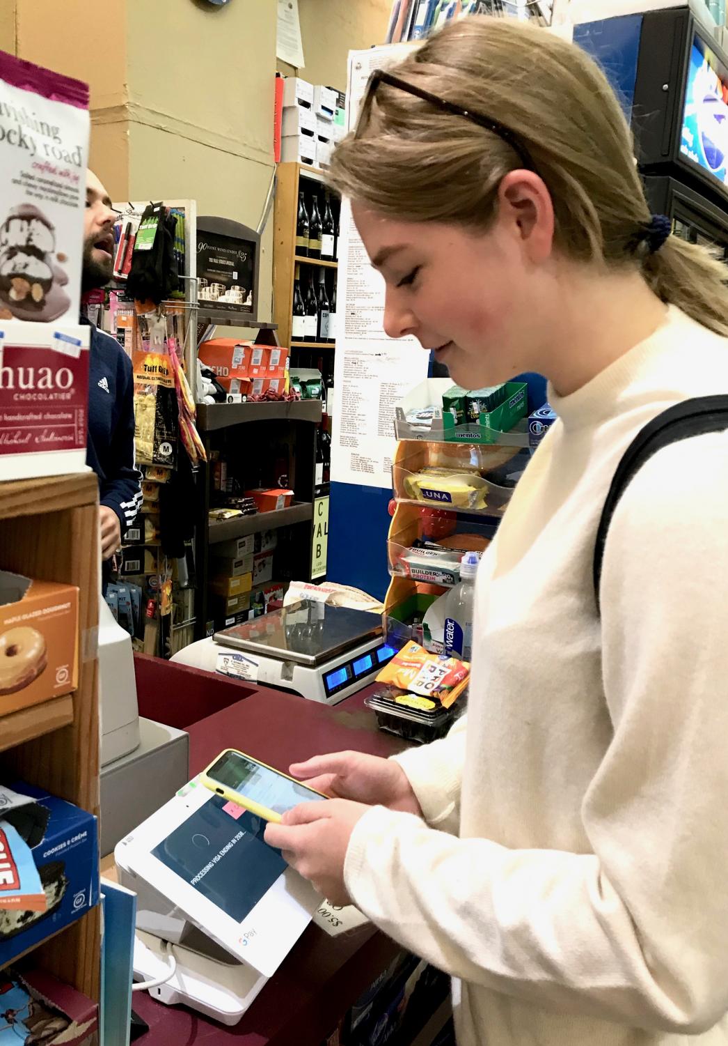 Senior Anna Doggett pays for her lunch at Mayflower Market using Apple Pay, like she does most days. Instead of cash, Doggett uses mobile payment methods more often than she uses cash or a debit card when purchasing her meals or buying products.
