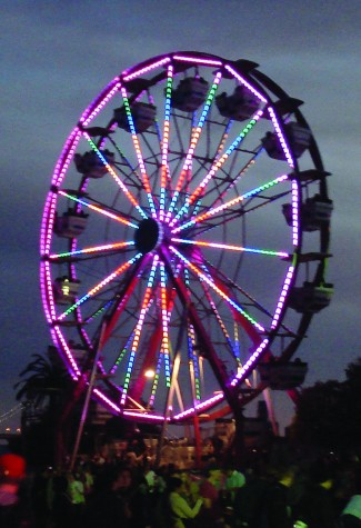 The annual 60 foot Ferris wheel lights up as the sky darkens. By nightfall it was an hour-long wait to ride.