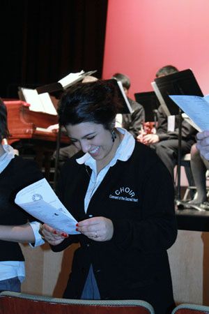Junior Elena Dudum checks lyrics at the annual Christmas Concert. She shared a solo as well as sang with the girls chorus and co-ed choir at the concert.