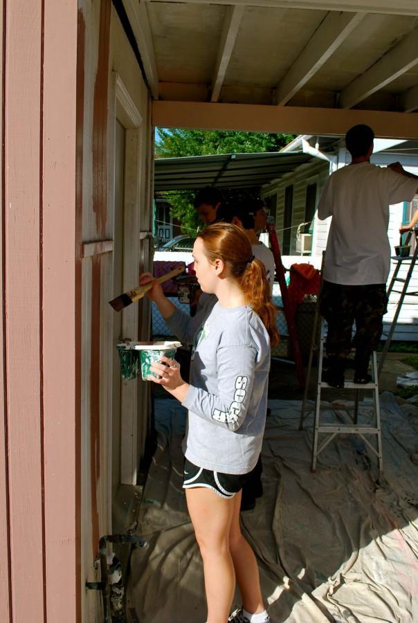 Junior Dakota Chamberlin paints the side of a house damaged by Hurricane Katrina. Students scraped and caulked the house the day before in preparation for painting. Photo: Ray OConnor