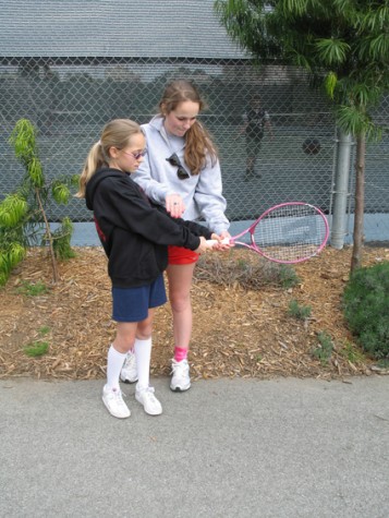 Anjali Shrestha | the broadview.  Delancie teaches Audrey Bjorklund how to properly hold and swing a racket at an after school tennis session. Bjorklund is one of 12 girls that she teaches after school tennis to.