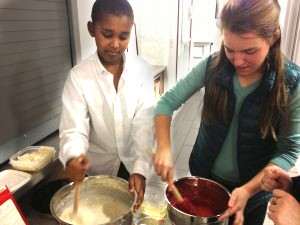 Senior Mary Katherine Michiels-Kibler and fifth grader Nahom Tesfaye mix cupcake batter. Cakes for a Cause held its first meeting today, after which members drove the desserts down to the Hamilton Family Center.