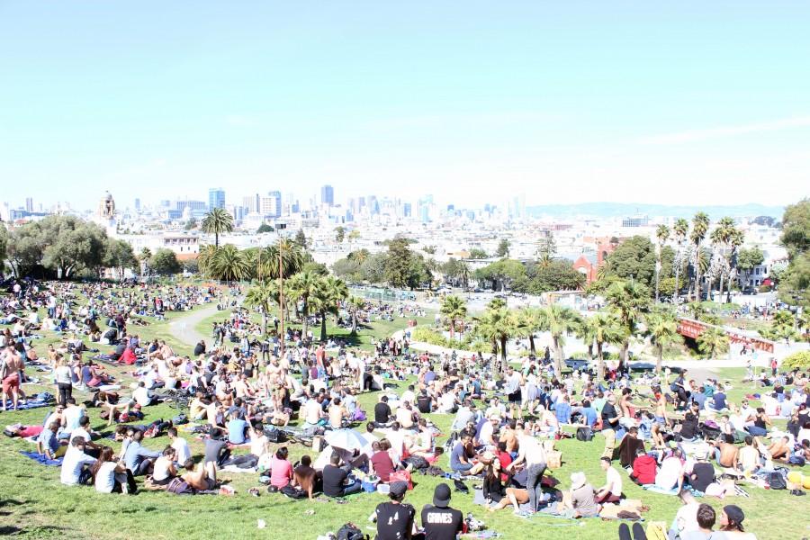 A large crowd basks in Mission Dolores Park on a warm Sunday afternoon.