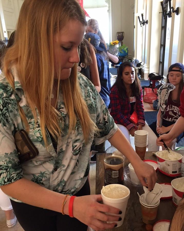 Sophomore Natalie Scheele grabs a spoon after buying a root beer float. Hot chocolate, donuts and pizza were also sold during the week.