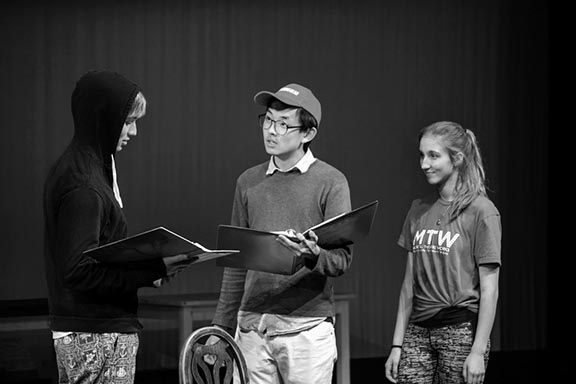 Seniors Duncan McDonell, Daniel Im and Catherine Heinen (from left) read their lines during a rehearsal for the school production of  “The Tempest”. The set features intricately designed lighting schemes and complex projections to add to the play’s aura of mystery and magic.