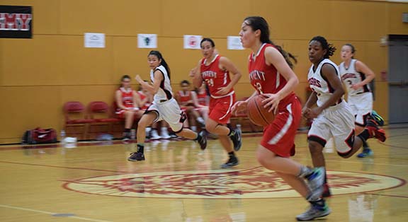 Junior Alyssa Alvarez dribbles the ball across the court during the last game of the Marin Academy Invitational Tournament. The team will play in a breast cancer awareness charity tournament beginning today.