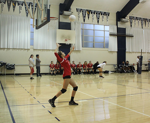 Sophomore Avery Van Natta eyes the ball in the air as she prepares to serve it over the net. Varsity volleyball fell short against Urban in its first league game, losing two sets to three.