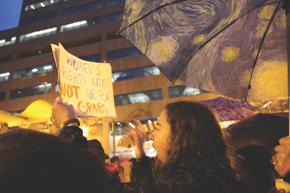 Senior Caroline Salveson holds a sign above her head while marching down Market Street. Salveson rallied beginning at 3 p.m. at Civic Center. 