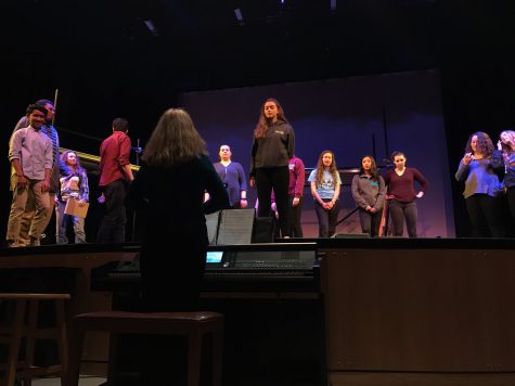 Sophomore Delaney Tobin stands center stage in her role as female protagonist Hope Cladwell while the Urinetown cast rehearse the show’s final number with music director Denise Wharmby. The cast and crew worked in tandem as actors and actresses rehearsed the first act while crew members assembled the set’s foundations.