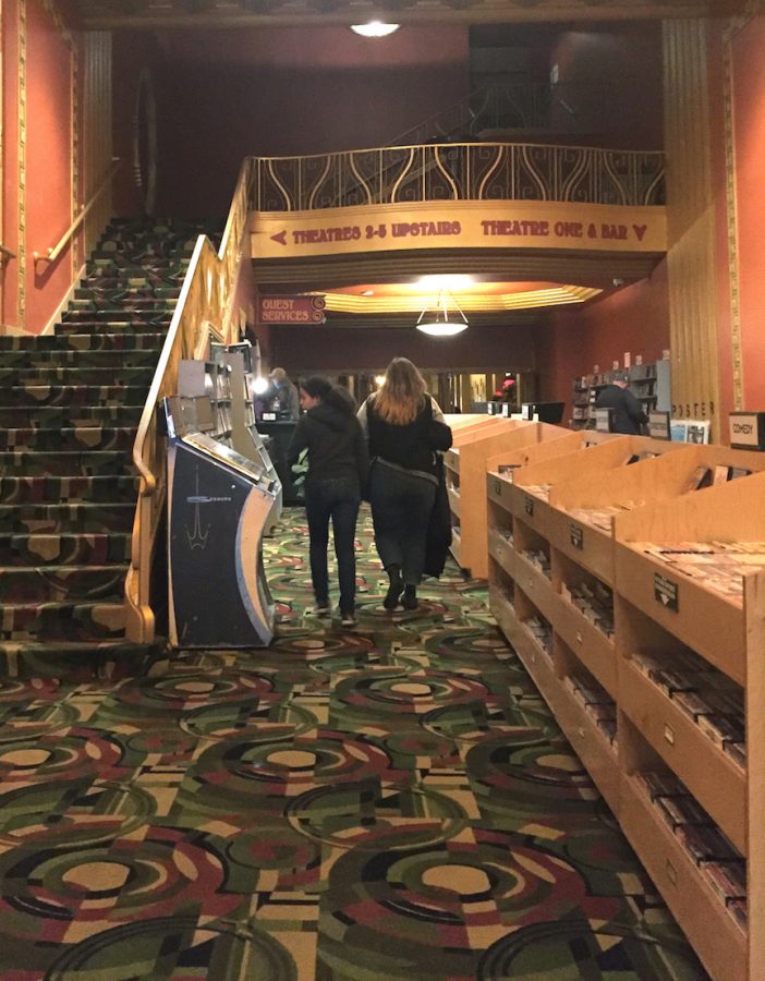 Cinema patrons walk past a vintage jukebox and shelves of VHS and DVD movies on sale on their way to an Alamo Drafthouse theater. Lost City Video runs a DVD sales and rental shop in the cinema lobby.