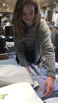 Senior Charlotte Cobb arranges a display during one of her shifts at the clothing store Brandy Melville. Cobb has worked at the Chestnut St. location for almost two years.