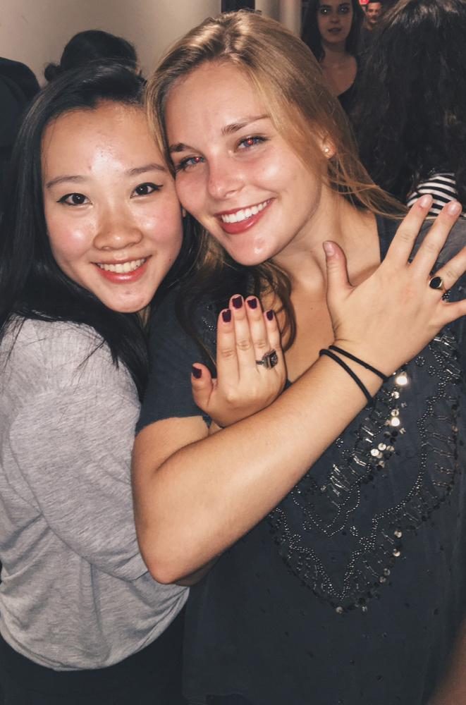 Sacred Heart Schools alumnae Liana Lum and Suzanne Antoniou pose holding their high school class rings, signifying they are members of a greater network of schools. Lum (‘16) graduated from Convent of the Sacred Heart in San Francisco, while Antoniou (‘16) attended Stone Ridge in Bethesda, Maryland. The two met at Brown University’s orientation and spoke of attending all girls schools.  