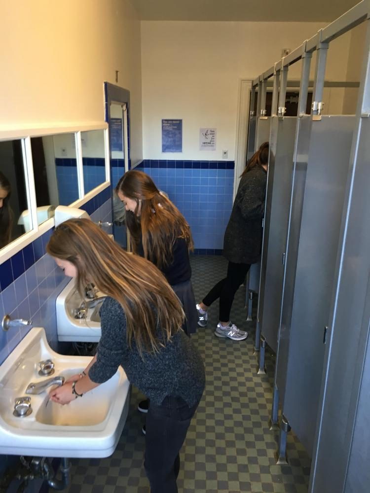 Sophomore Elizabeth Worthington and junior Sinead McKeon wash their hands in the second floor bathroom of the Flood Mansion that was last updated in the 1940s. Antiquated plumbing contributes to frequent clogging of the pipes.