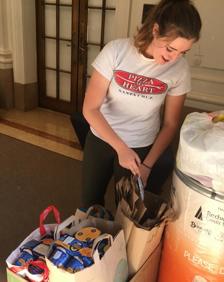 Junior Caroline Phillipps puts food into a donation bin for victims of the North Bay fire. The drive, which started Monday, ends today.