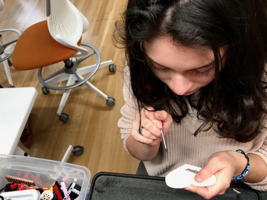 Art Council Representative Isabella Bermejo cleans up the edges of the words California Strong on a heart-shaped pin. After the edges are clean, the pins will be spray painted purple before being sold. 