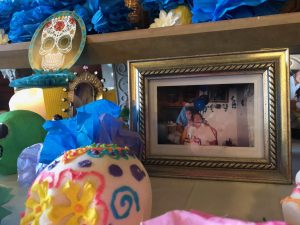 Sophomore Malinali Cervantes leaves a photo of her deceased grandfather on the Dia de los Muertos altar in the chapel. Students and faculty were invited to place an item on the altar in remembrance of loved ones that have died.