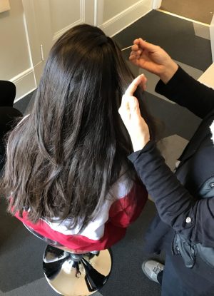 A junior gets her hair checked by a worker for Lice Patrol during B Period. Due to an outbreak of lice, all soft furniture on campus will be cleaned and Lice Patrol will return to campus later this month to re-check students.