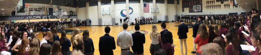 Students and faculty stand in the Stuart Hall gym as teacher Paul Pryor-Lorentz speaks to the audience to begin the Ash Wednesday service. The ceremony was held before first period and consisted of individuals from Convent and Stuart Hall High School. 