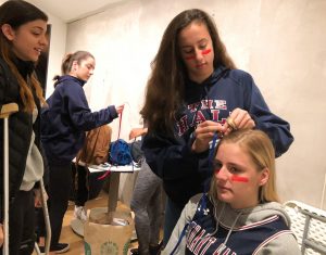 Sophomore Isabelle Thiara braids junior Grace Boudreau’s hair adding red and blue ribbon, the team’s colors. The Syufy Theatre was filled with the Knight’s colors and spirit before the game, as almost all students have some sort of accent in their hair, on their face or around their body. 