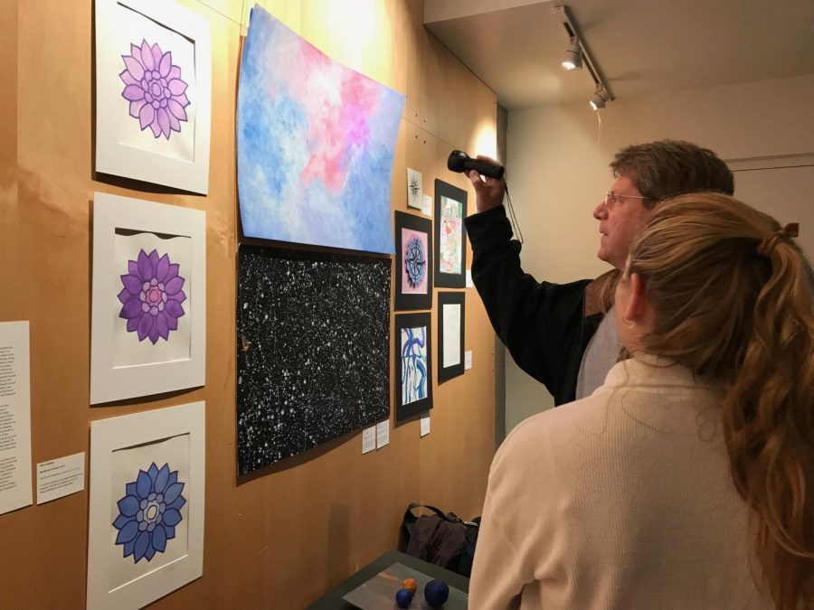 Students and parents explore Olivia Matthes’ art pieces during the exhibition. Along with Matthes, many students incorporated an interactive aspect to their pieces — including shining light, music and turning pages.