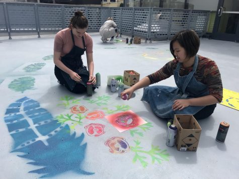 Sophomores Cat Webb-Purkis and Abby Widjanarko spray paint California poppies and bald eagle feathers on the art terrance floor. The mural incorporates all elements of STEAM.  