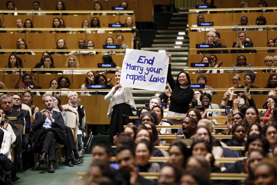 Joëlle Santos 09, right, holds up a sign at the International Womens Day celebration. Other U.N. Women raised awareness for movements such as #MeToo and #TimesUp.