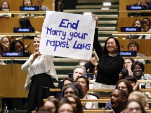 Joëlle Santos 09, right, holds up a sign at the International Womens Day celebration. Other U.N. Women raised awareness for movements such as #MeToo and #TimesUp.