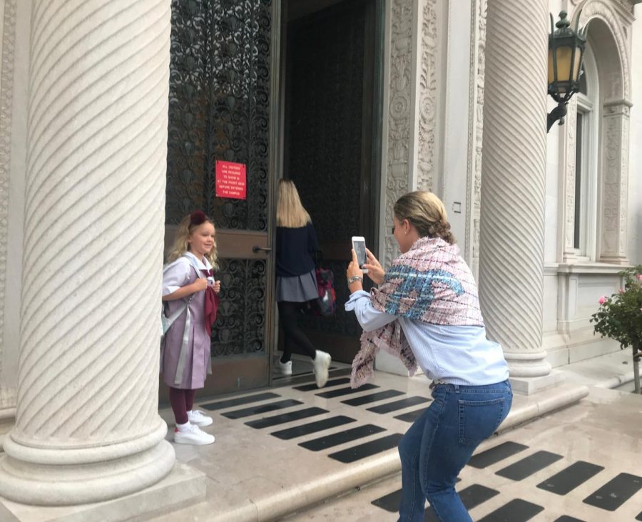 Mother takes a photo of her daughter on the first day of school. Grades K to 12 began school today at 8 am.
