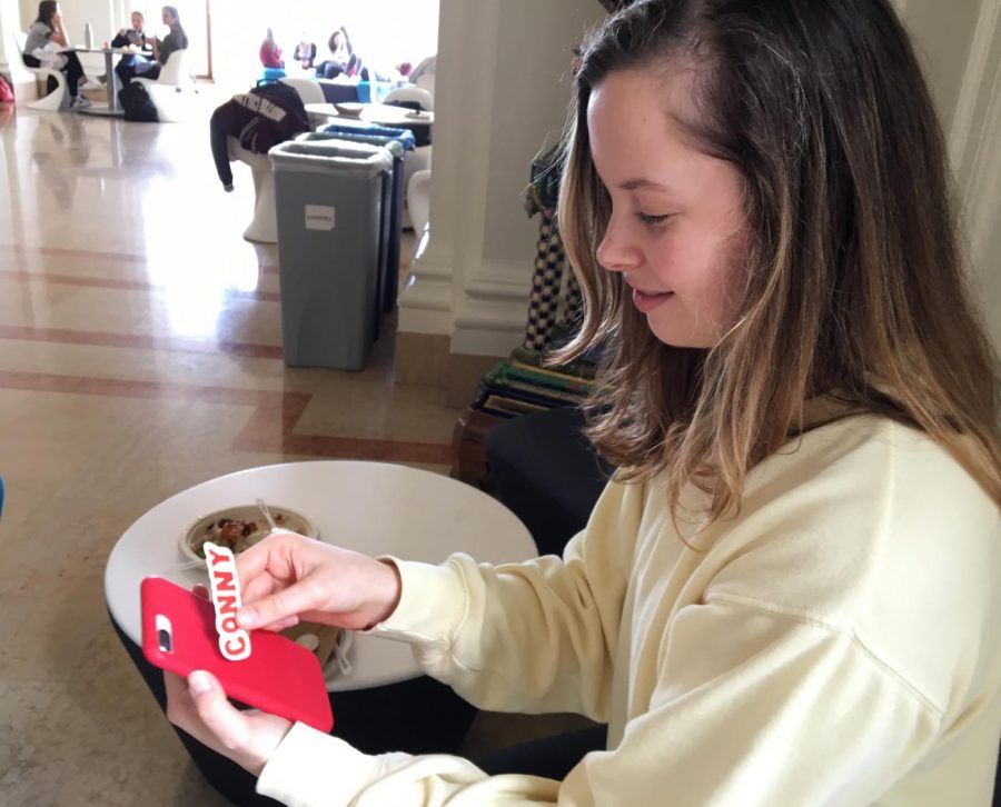 Senior Emma Hubbard holds a Conny sticker against her iPhone in the Main Hall. Student Council began selling Conny, Slay and RV, standing for Robust Vulnerability, stickers today to fundraise for dances and Congé.