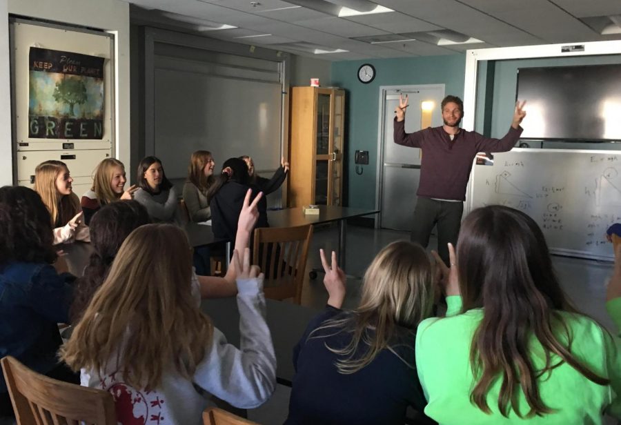 Spanish students sing with hand motions during the Noёls rehearsal with Spanish teacher Anthony Reyes. The peace signs represent the line gente de paz, meaning people of peace. 