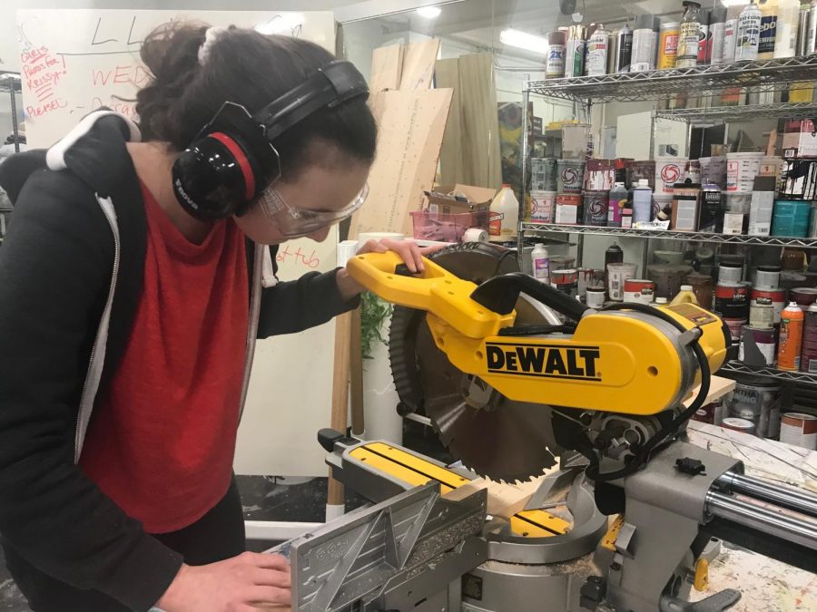 Freshman Alia Mogannam uses a saw to construct a piece of the set. The crew spends about 10 hours a week working on the show. 