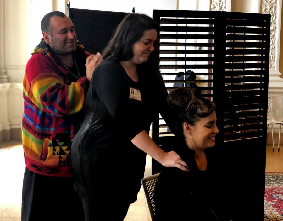 Masseuse Carlos Hu demonstrates on Nicole Holt how to apply pressure to the shoulders in order to relieve tension. Hu, Holt, and Nina Stavinga were at the end of their shift, having given chair massages to faculty and staff throughout the day.