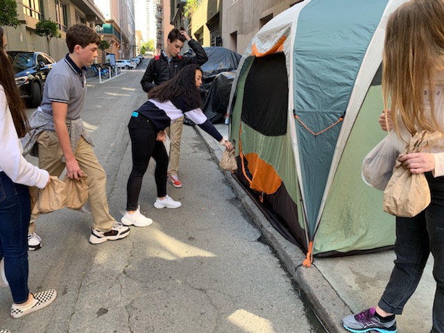 Freshman+Shelby+Low+hands+out+a+lunch+to+someone+living+on+the+streets+of+the+Pol+Gulch+district+in+San+Francisco.+The+freshman+class+made+and+passed+out+lunches+for+their+Freshmen+Signature+Service+Project.
