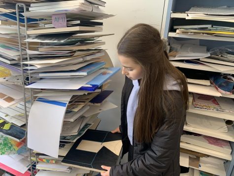 Freshman Adele Fratesi places her “All Summer in a Day” inspired art project on the drying rack. Her project portrays a dark room with a small amount of light shining through.
