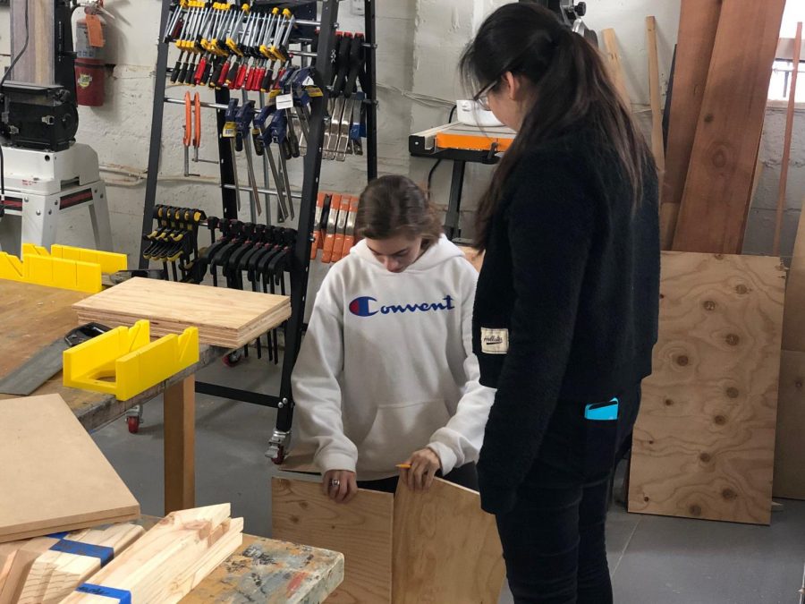 Junior Zoe Hinks and Michelle Wang measure the dimensions of a dollhouse they are creating for their International Baccalaureate Creativity, Activity and Service Project. They have been working on the project since February in the Herbst House wood shop.