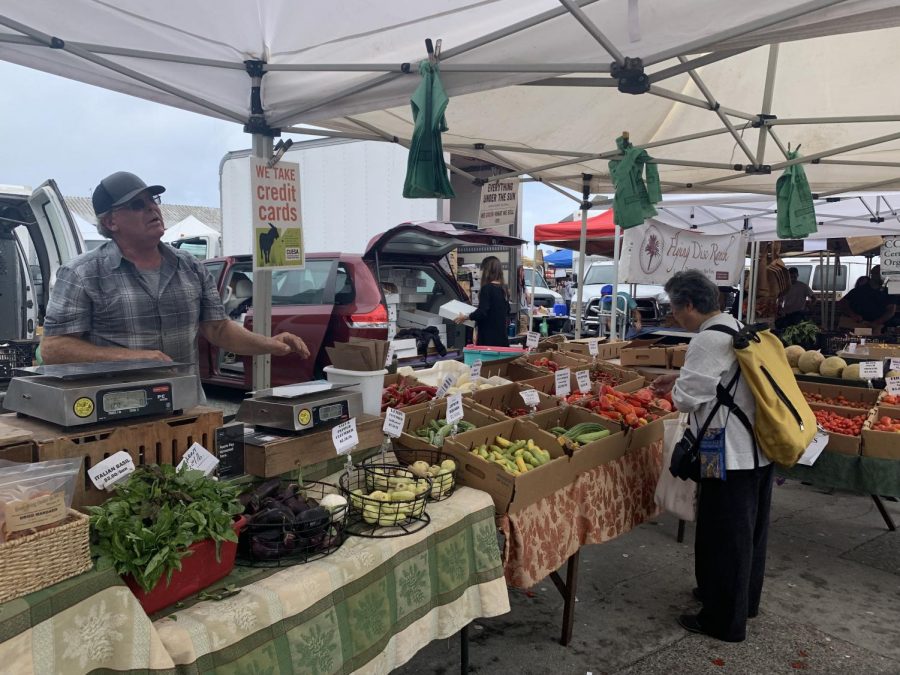 Farmer Bill Crepps of the farm Everything Under the Sun sells his dried fruit to a customer at the Ferry Plaza Farmers Market. Crepps farms his fruits and vegetables using sun-drying methods that achieve organic status and employ sustainable methods. 
