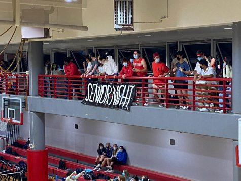 Student fans support the varsity volleyball players and watch from behind the student-made banner. Many family and faculty members came to watch the game to support the seniors. 
